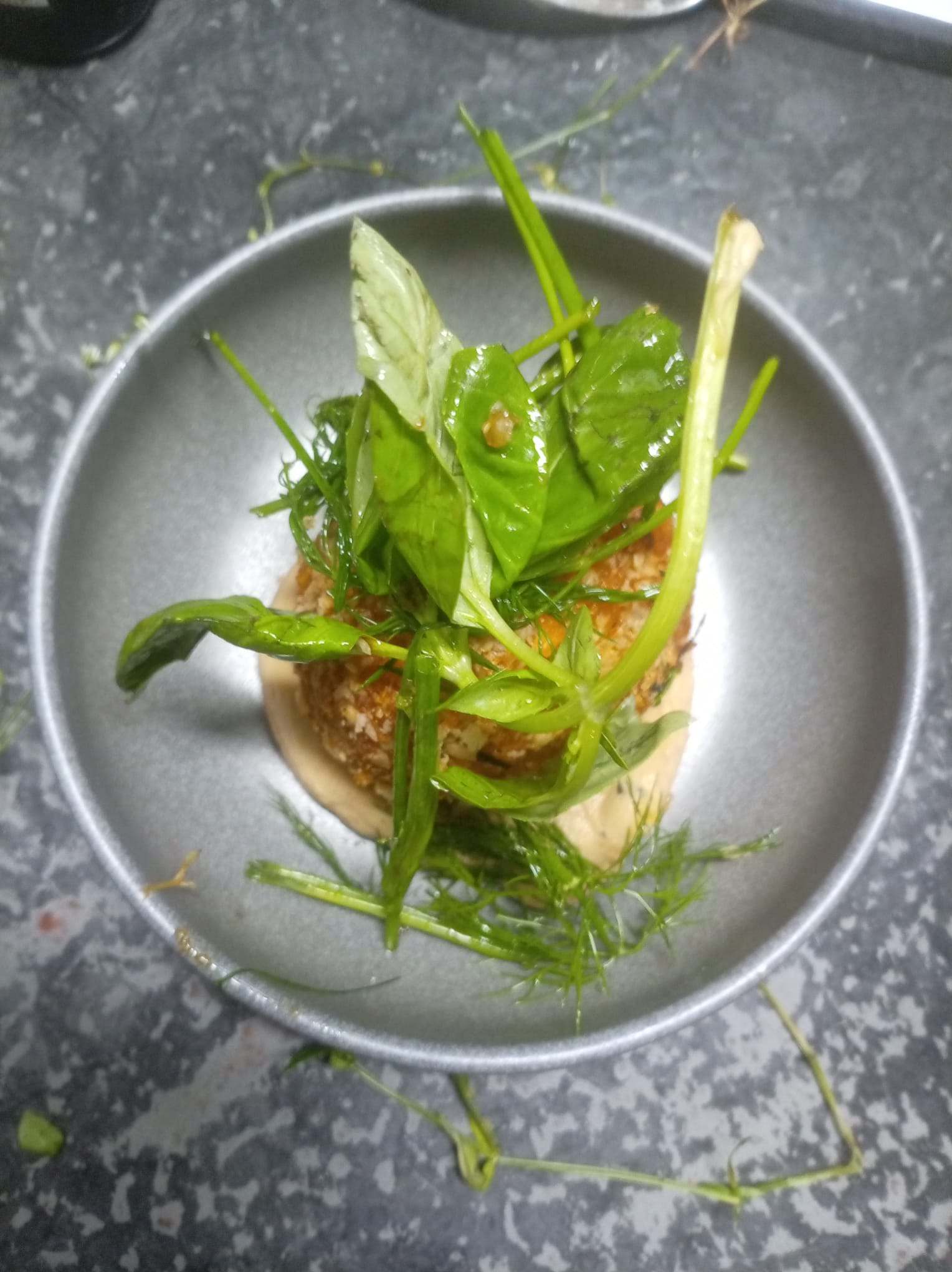 A tall plated dish of young shoots and fresh herbs.