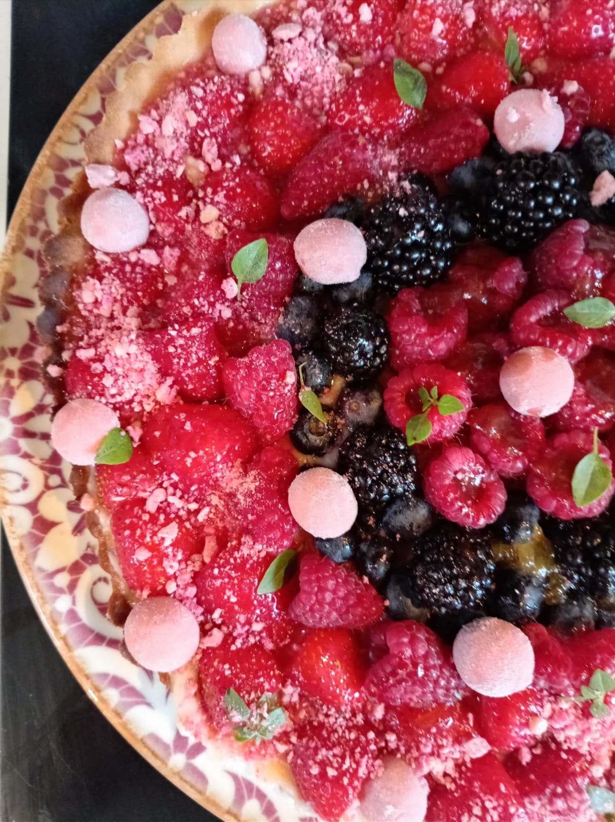 Large red fruit tart: raspberries, blackberries, blueberries and small pink meringues.