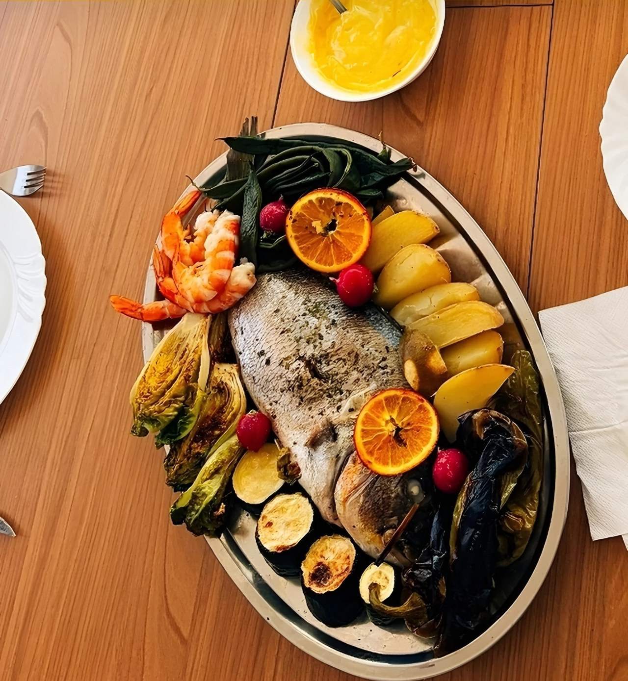 Sharing platter: whole roasted fish, prawns, potatoes, grilled vegetables and oranges.